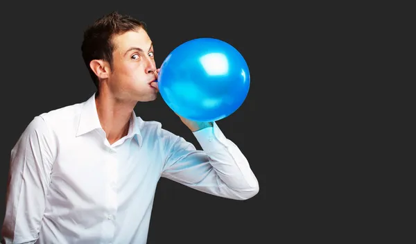 Portret van jonge man opblazen van de ballon — Stockfoto