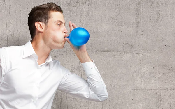 Ritratto di giovane uomo che soffia un palloncino — Foto Stock