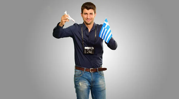 Fotógrafo segurando bandeira da Grécia e avião em miniatura — Fotografia de Stock