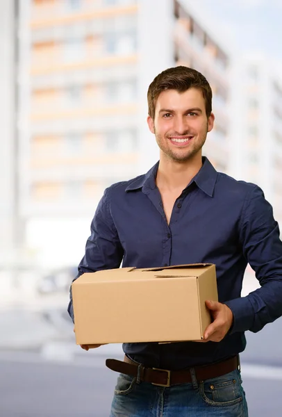 Joven hombre sosteniendo la caja de cartón — Foto de Stock