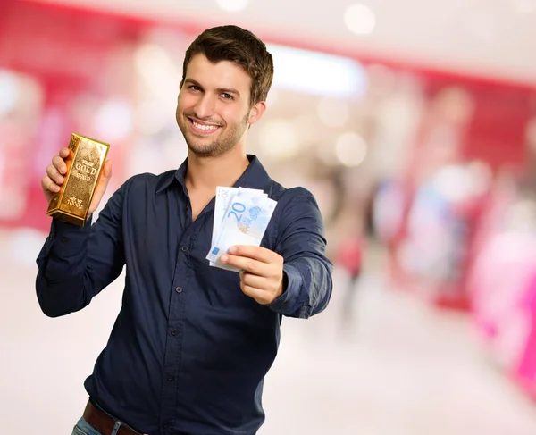 Genç adam tutarak altın bar ve euro para birimi — Stok fotoğraf