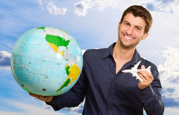 Jonge man houden globe en miniatuur — Stockfoto