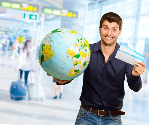 Jonge man houden globe en boarding pass — Stockfoto