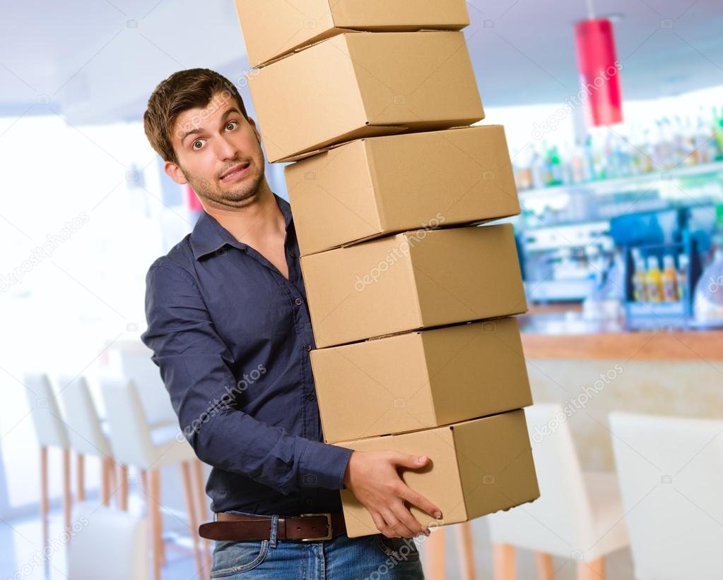 Young Man Holding Stack Of Cardboxes