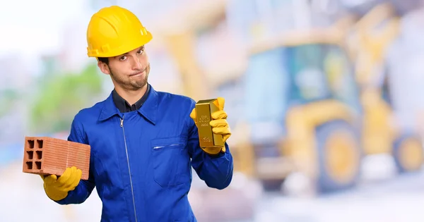 Engenheiro segurando tijolo e Goldbar — Fotografia de Stock