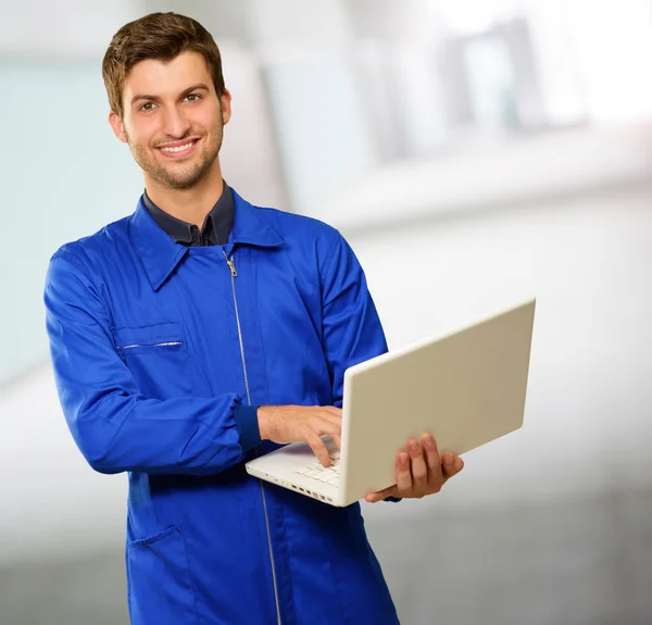 Gelukkig jonge technicus die op laptop werkt — Stockfoto