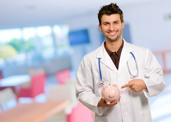 Jovem Doutor Segurando Piggy Bank Gesturing — Fotografia de Stock