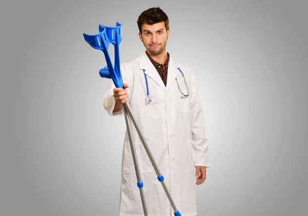 Young Male Doctor Holding Crouches — Stock Photo, Image