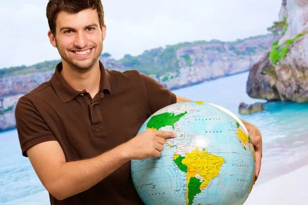 Giovane uomo che mostra la destinazione sul globo — Foto Stock
