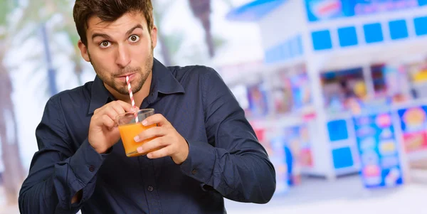 Ung man dricker juice genom sugrör — Stockfoto