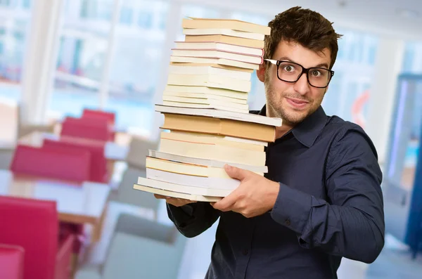 Jonge man met stapel boeken — Stockfoto