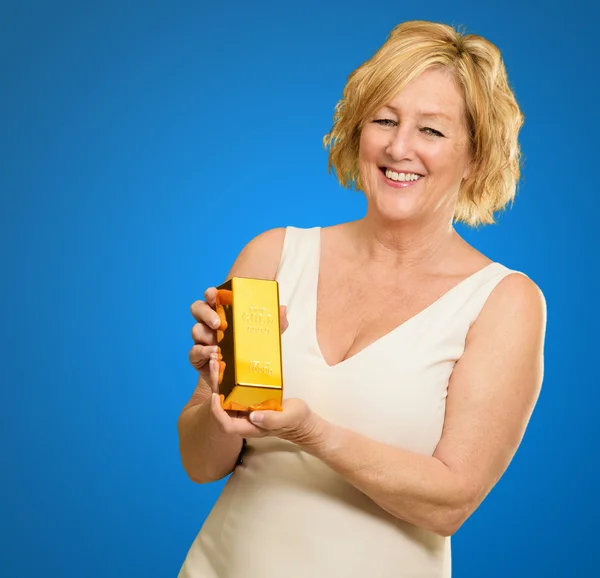 Mujer feliz sosteniendo Goldbar sobre fondo azul — Foto de Stock