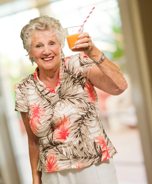 Starsza kobieta przytrzymanie sok szkło — Zdjęcie stockowe