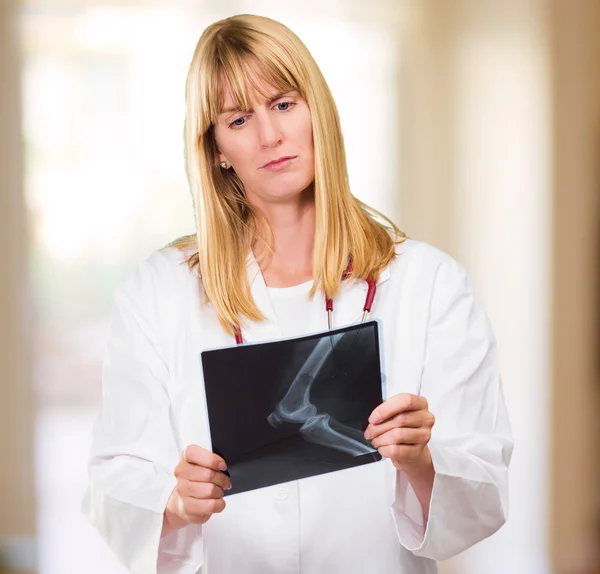 Alvorlig doktor kigger på et røntgenbillede - Stock-foto