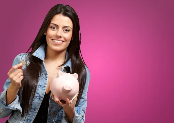 Retrato de una hembra sosteniendo una moneda y una hucha — Foto de Stock