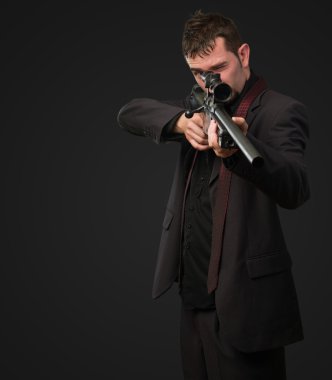 tüfekle işaret eden takım elbiseli adam