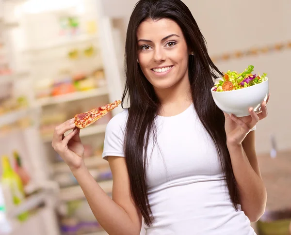 Nő, kezében egy darab Pizza és Saláta tál — Stock Fotó