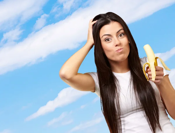 Une jeune femme mange une banane — Photo