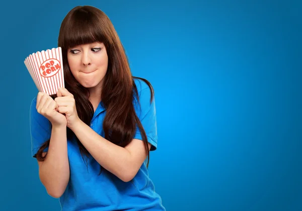 Girl holding empty popcorn packet — Stock Photo, Image