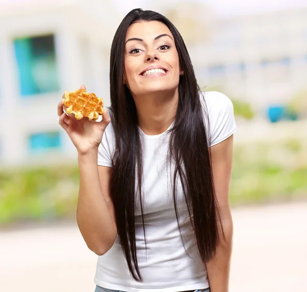 Uma jovem mulher segurando e mostrando no waffle — Fotografia de Stock