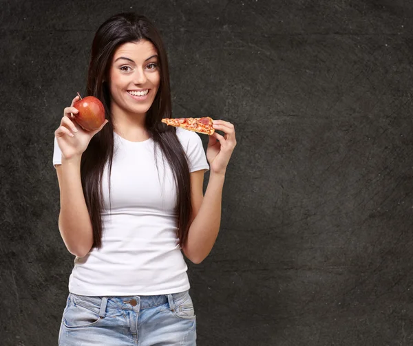 Mujer sosteniendo un pedazo de pizza y una manzana —  Fotos de Stock