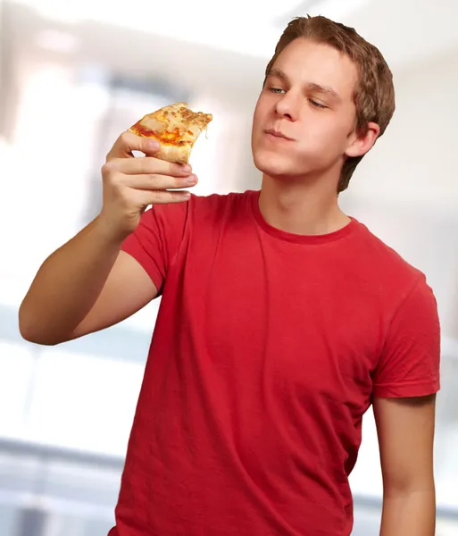 Portrait d'un jeune homme mangeant une pizza — Photo