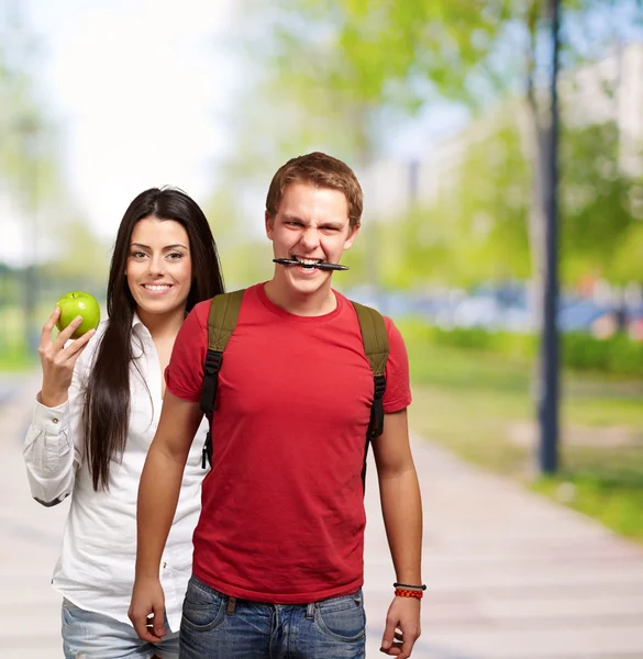 Estudantes segurando caneta e frutas — Fotografia de Stock