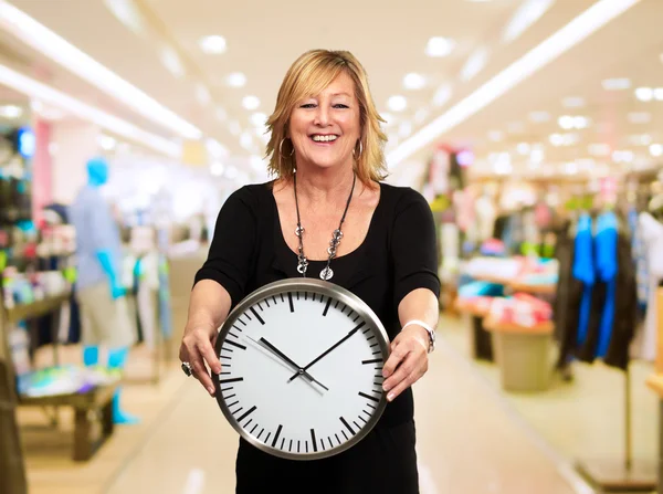 Mujer mayor sosteniendo reloj de pared — Foto de Stock