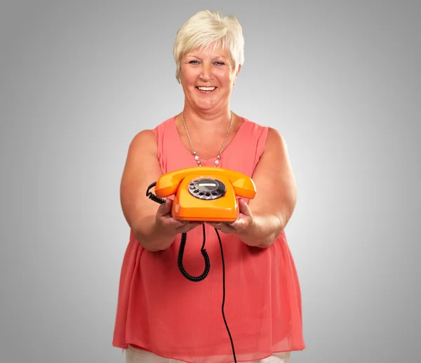 Retrato de uma mulher sênior segurando um telefone retro — Fotografia de Stock