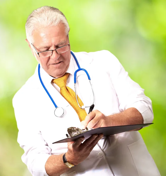Старший чоловік лікар пише на кишені — стокове фото