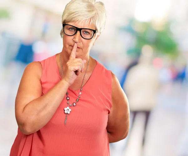 Senior vrouw met vinger op lippen — Stockfoto