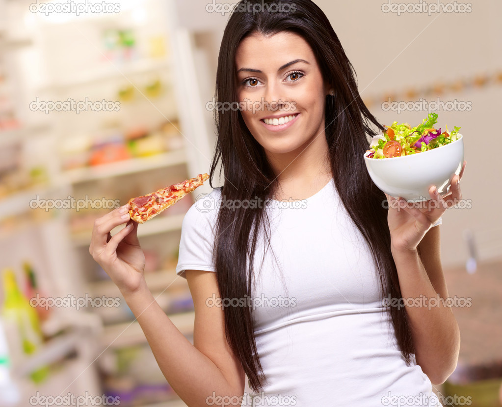 Female Holding A Piece Of Pizza And Salad Bowl
