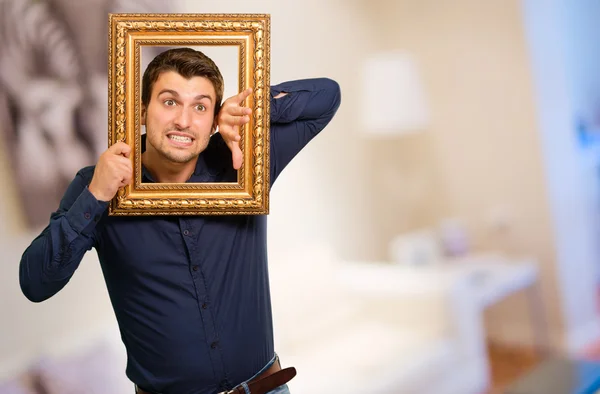 Hombre joven sosteniendo marco de imagen —  Fotos de Stock