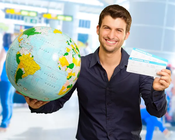 Homem jovem segurando globo e embarque passagem — Fotografia de Stock