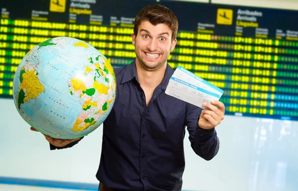 Jeune homme tenant Globe et carte d'embarquement — Photo