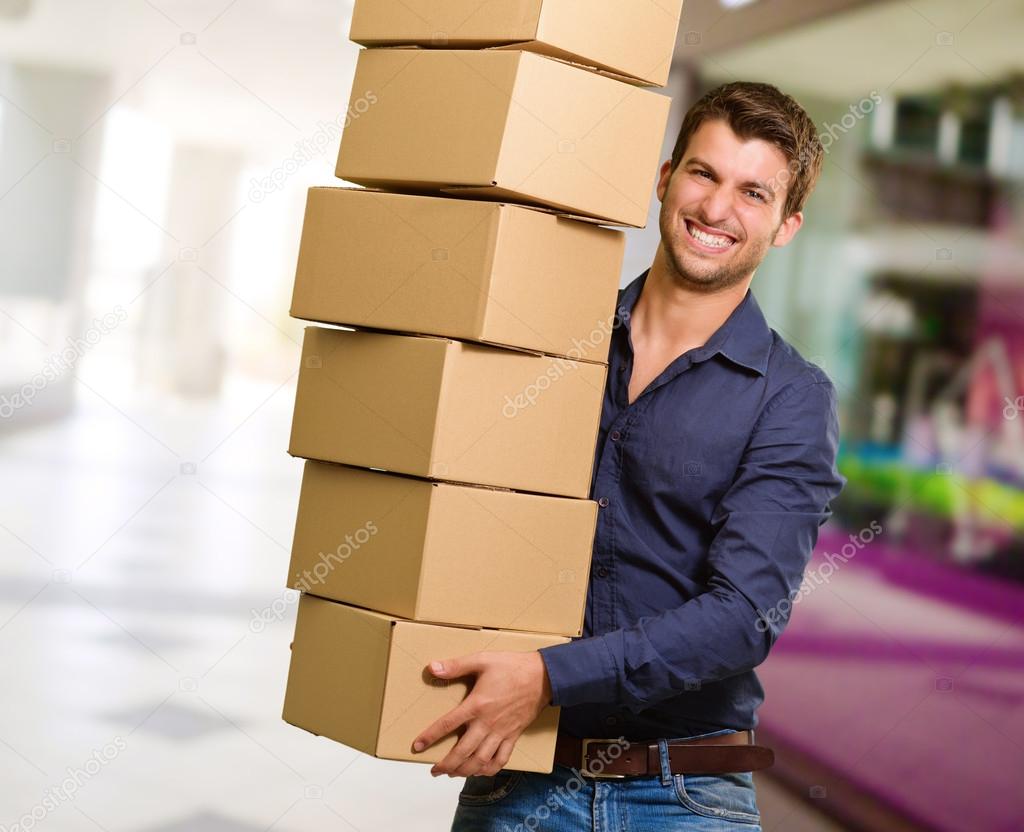 Young Man Holding Stack Of Cardboxes