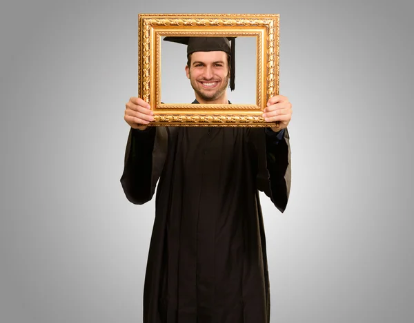 Hombre graduado mirando a través de un marco —  Fotos de Stock