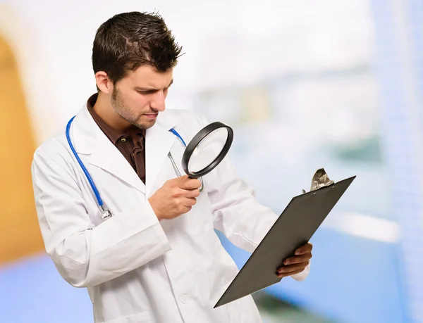 Médico jovem olhando através de lupa — Fotografia de Stock