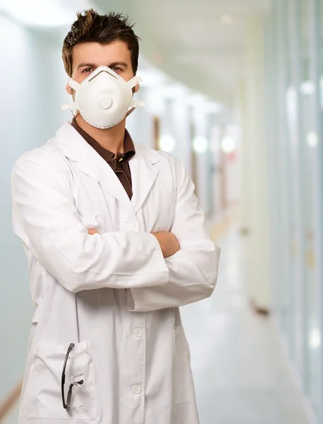 Giovane medico indossando maschera con le mani piegate — Foto Stock