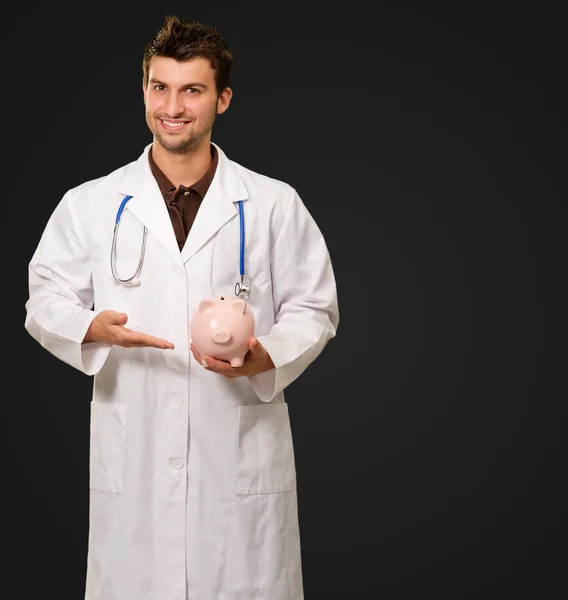 Jovem médico segurando porquinho banco — Fotografia de Stock