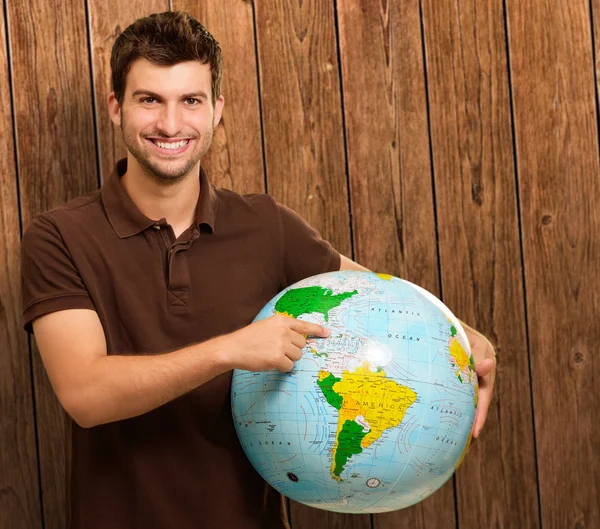 Homem jovem mostrando destino no globo — Fotografia de Stock