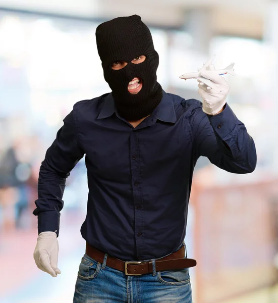 Hombre usando máscara de ladrón y sosteniendo miniatura de avión — Foto de Stock