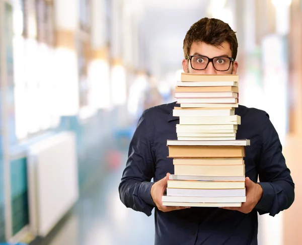 Jovem segurando pilha de livros — Fotografia de Stock