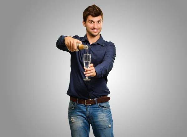 Gelukkig jonge man gieten champagne in glas — Stockfoto