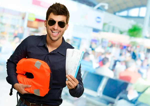 Hombre feliz sosteniendo chaleco salvavidas y tarjeta de embarque — Foto de Stock