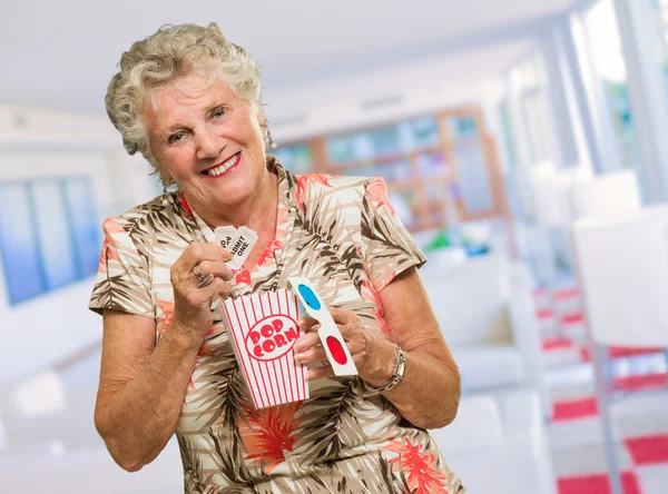 Mujer mayor comiendo palomitas de maíz viendo 3d película — Foto de Stock