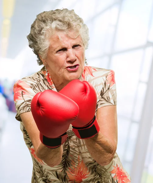 Mujer madura enojada usando guantes de boxeo — Foto de Stock