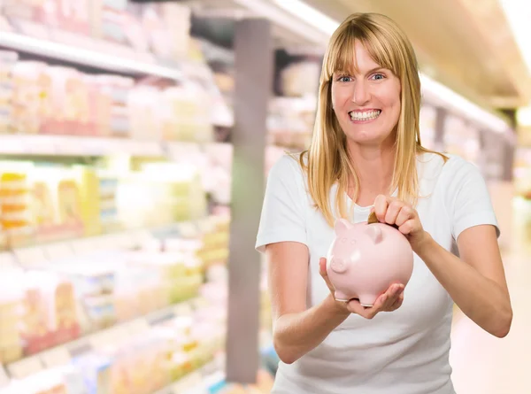 Frau steckt Münze in Sparschwein — Stockfoto