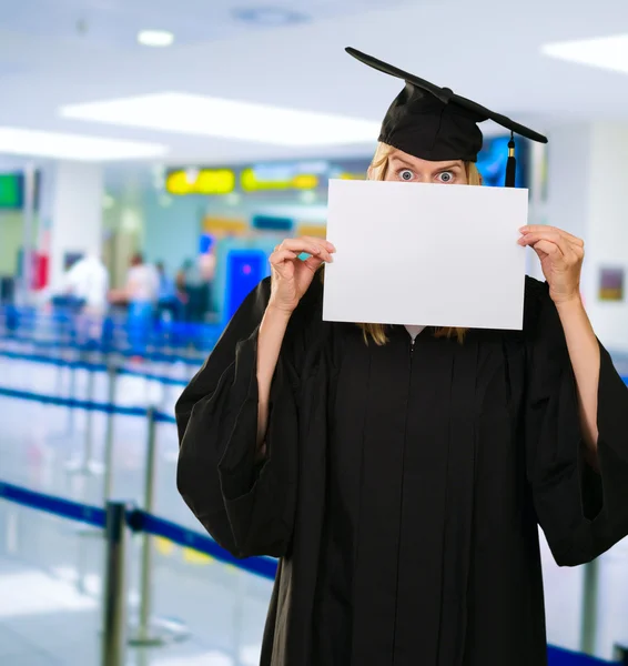 Afgestudeerde vrouw verstopt achter een blanco papier — Stockfoto