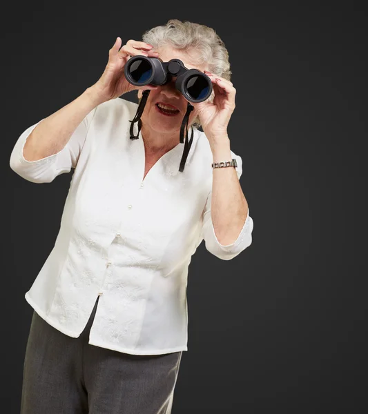 Porträt einer Seniorin, die durch ein Fernglas blickt — Stockfoto